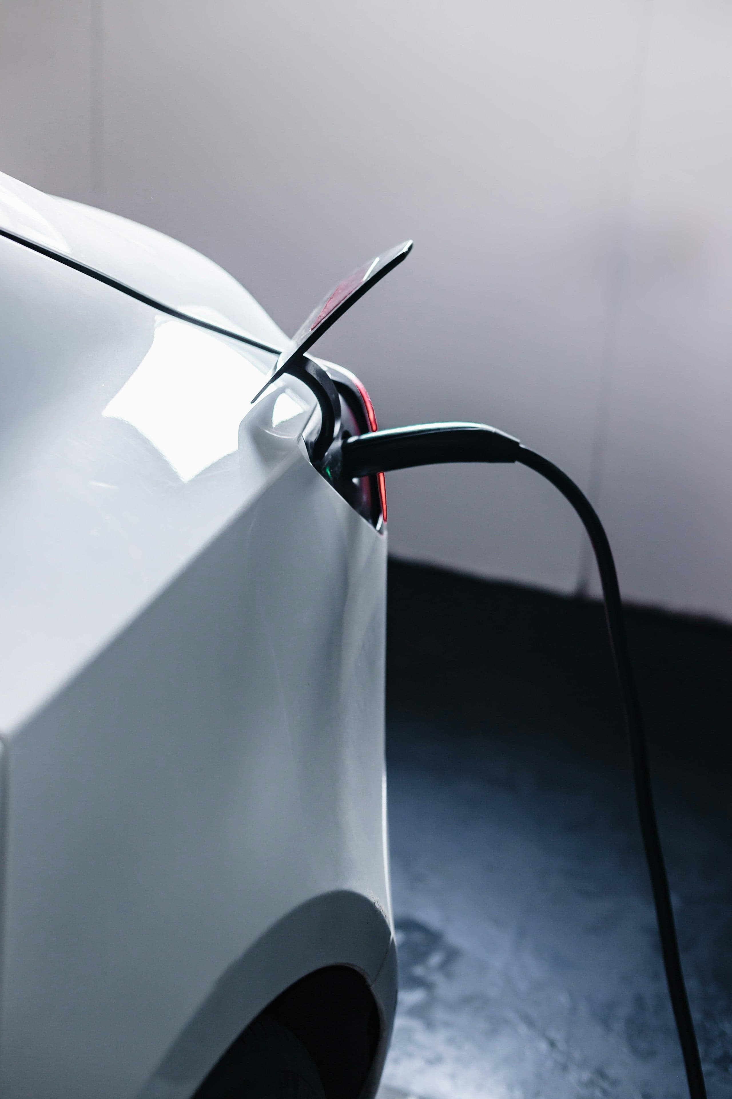 Weißes Elektroauto in der Nahaufnahme, Ladekabel steckt in der geöffneten Ladebuchse